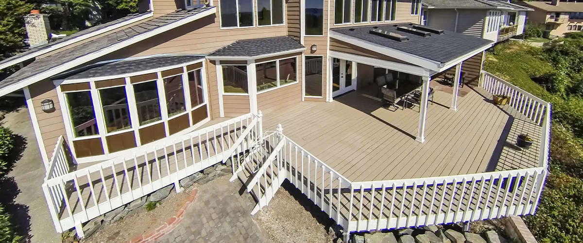 Spacious Deck Design In Plano with white railing, attached to a large house, under clear blue sky.