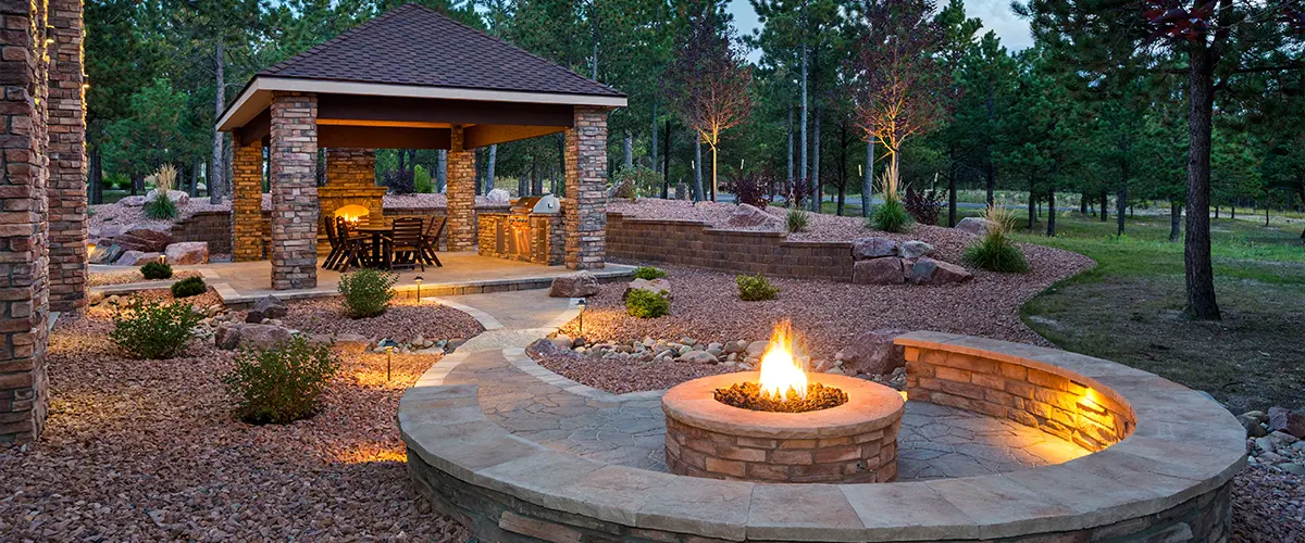 Beautiful outdoor patio with stone fire pit, covered dining area, and landscaped garden, perfect for backyard entertaining and relaxation.