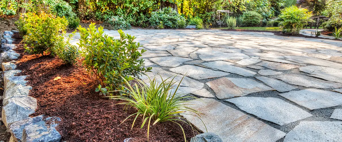 Completed flower beds around new stone patio with plants in place