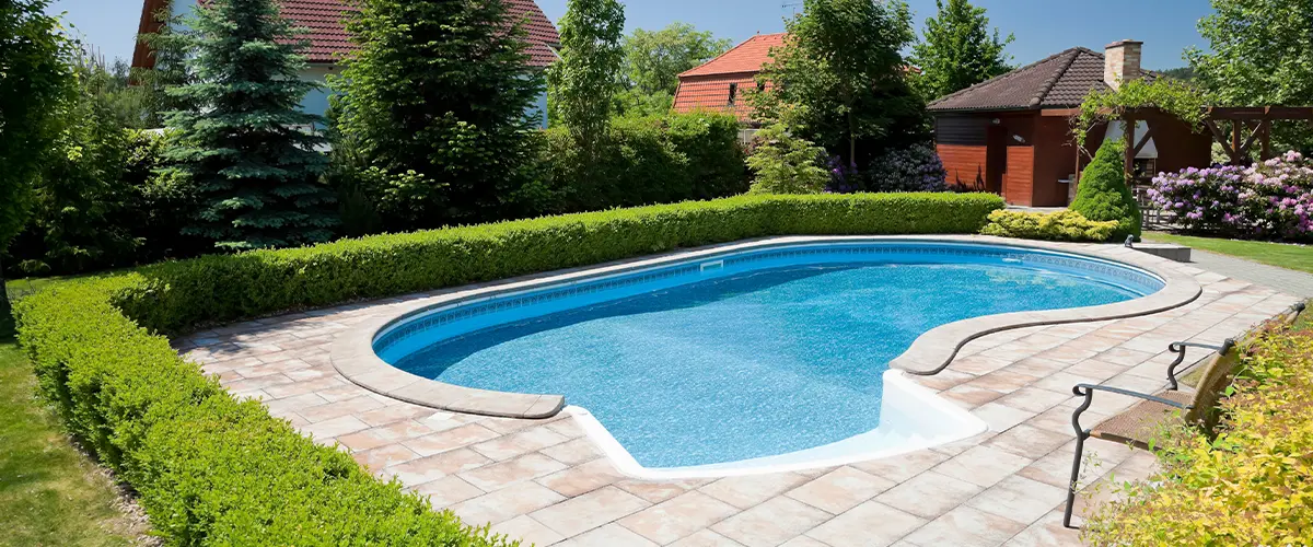 Charming backyard swimming pool design in Plano. with tiled deck, nestled in lush green garden landscape