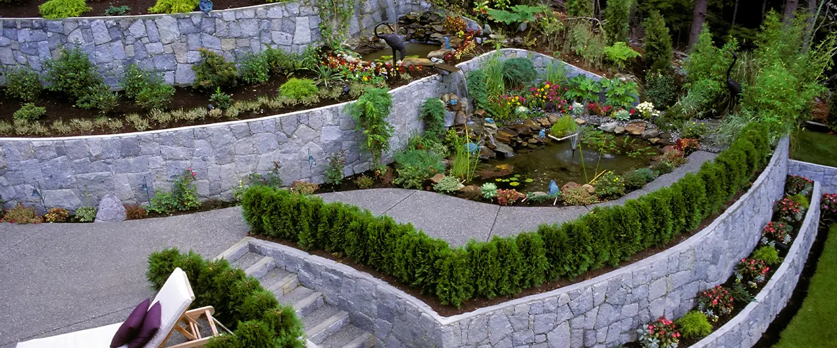 Terraced garden with stone retaining walls, vibrant flowers, and lush greenery for a tranquil backyard retreat.