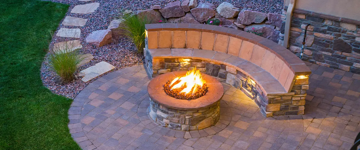 Beautiful backyard patio with a stone firepit and curved seating area.