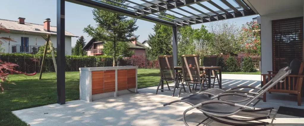 Backyard pergola with an outdoor dining setup and lounge chairs under a shaded structure.